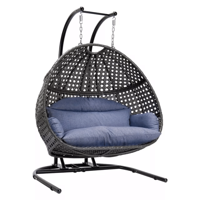 A person relaxing in a white wicker swing chair on a patio.