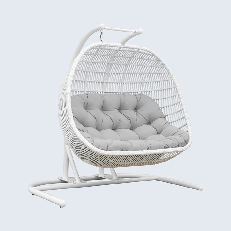 Freestanding double porch swing with gray cushion on a patio.