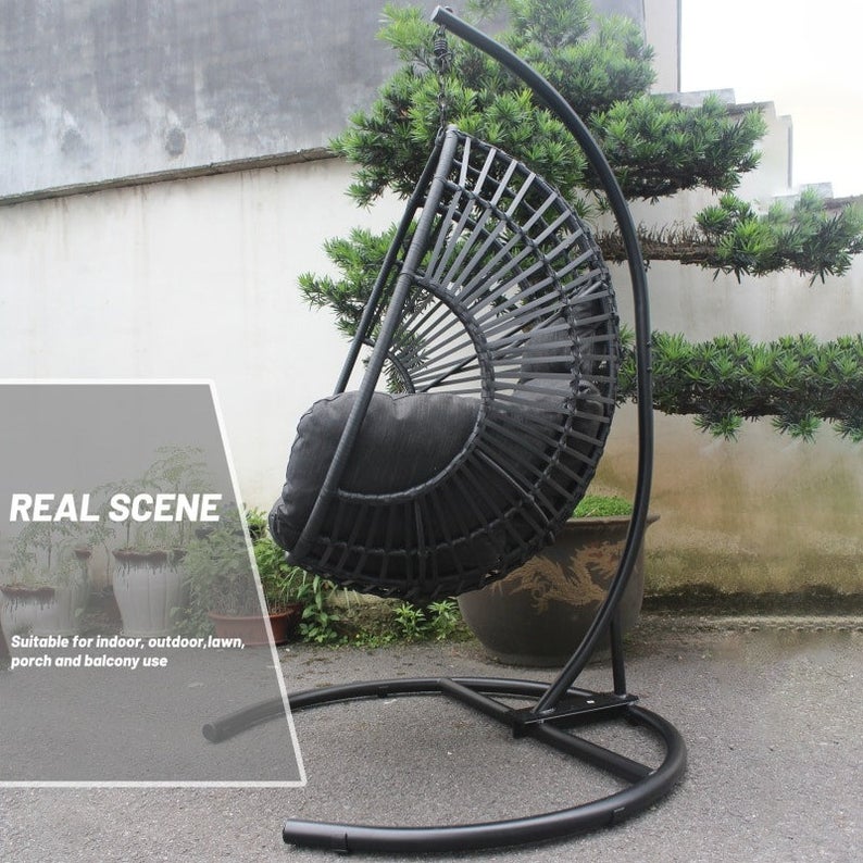 A person relaxing in a white wicker egg swing chair on a patio.