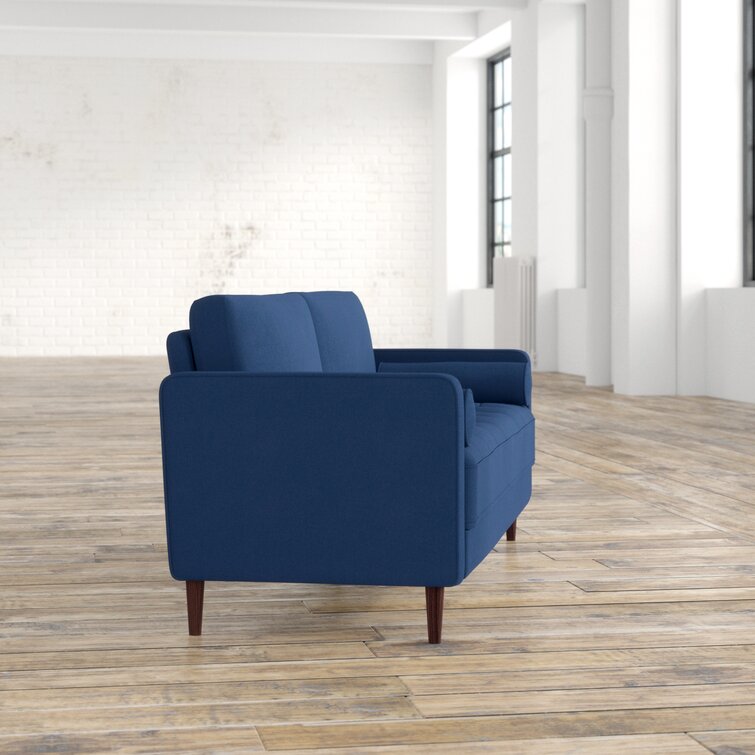 A modern sofa with square arms and tufted upholstery in a living room.