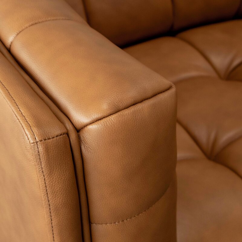 The flared arm design of a contemporary leather sectional.