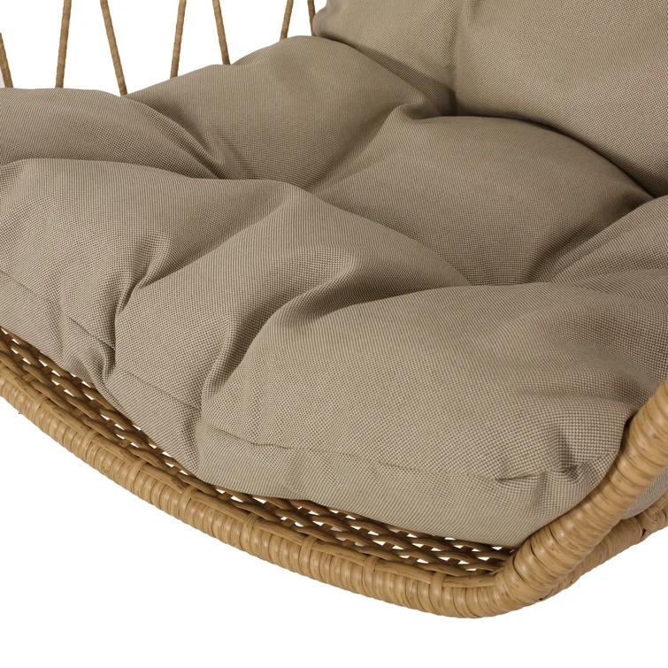A person sitting on a gray cushioned porch swing hanging from a ceiling.